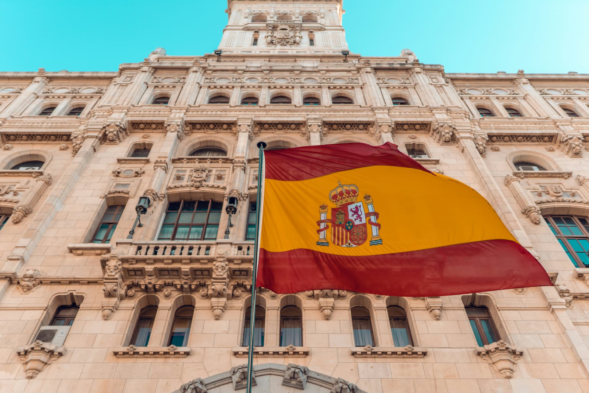 Spanish flag flying in front of an ornate stone building