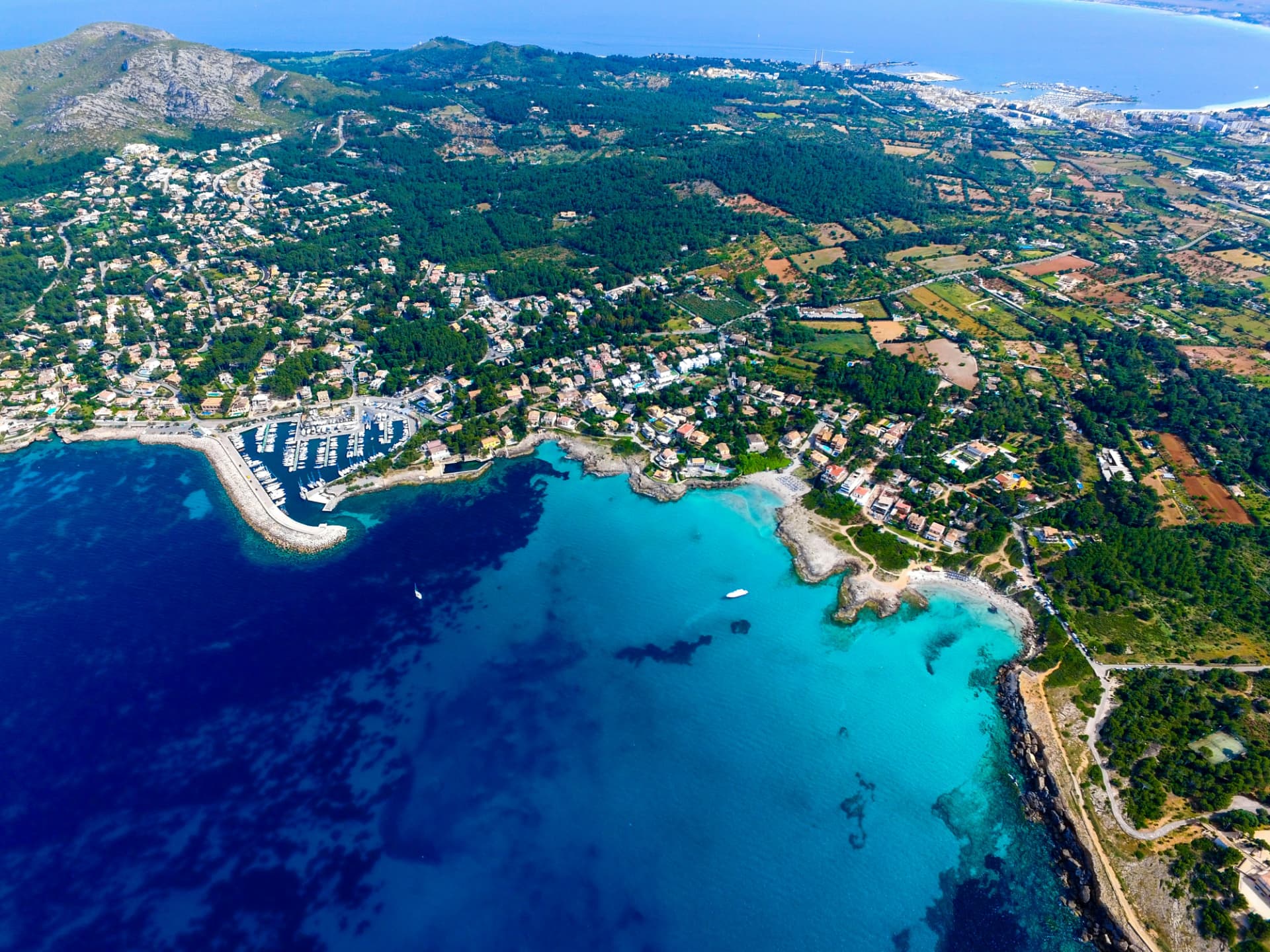 Aerial view of a marina and turquoise bay on the Mallorca coast